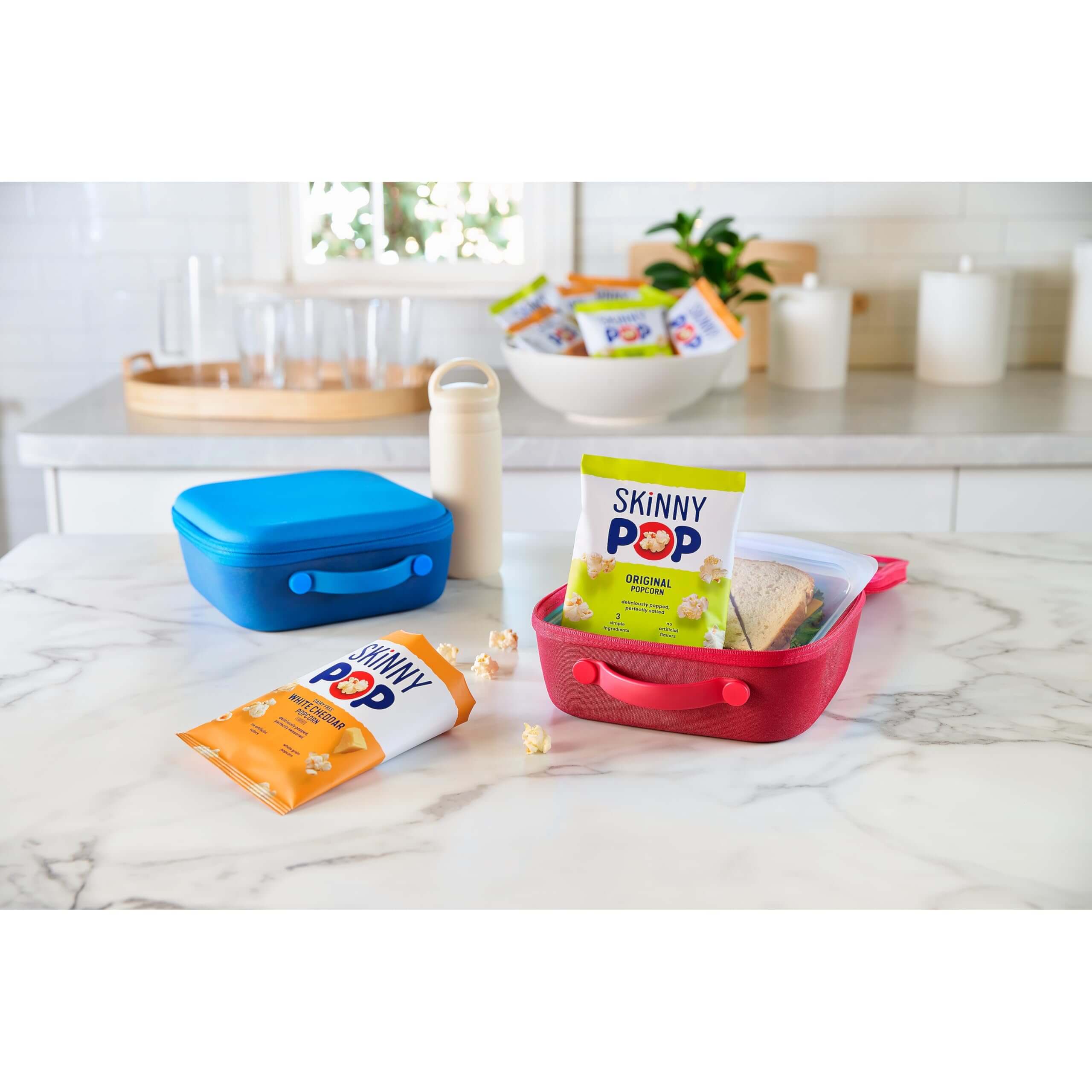 SkinnyPop Family Favorite Variety Pack snacks in colorful containers on a kitchen countertop.