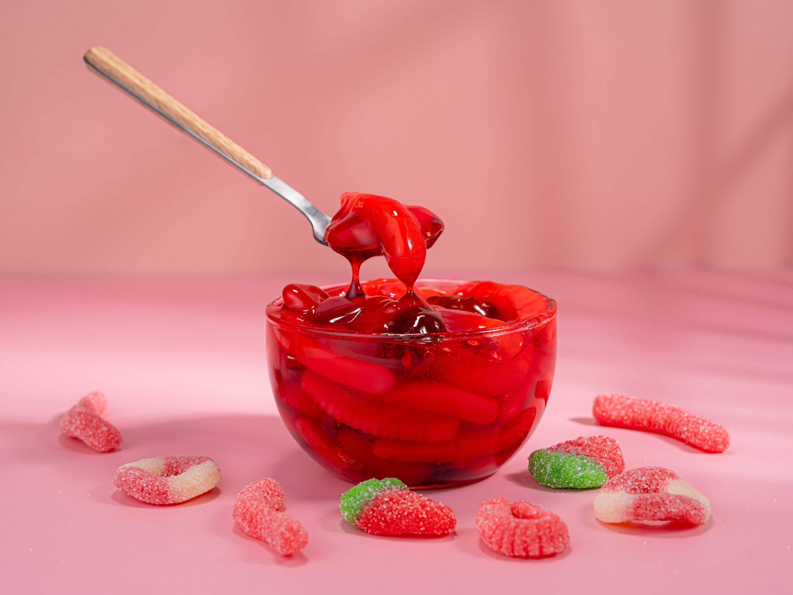 Viral Sour Gooey Gummies in a bowl with a spoon, showcasing vibrant strawberry flavor and gooey texture.