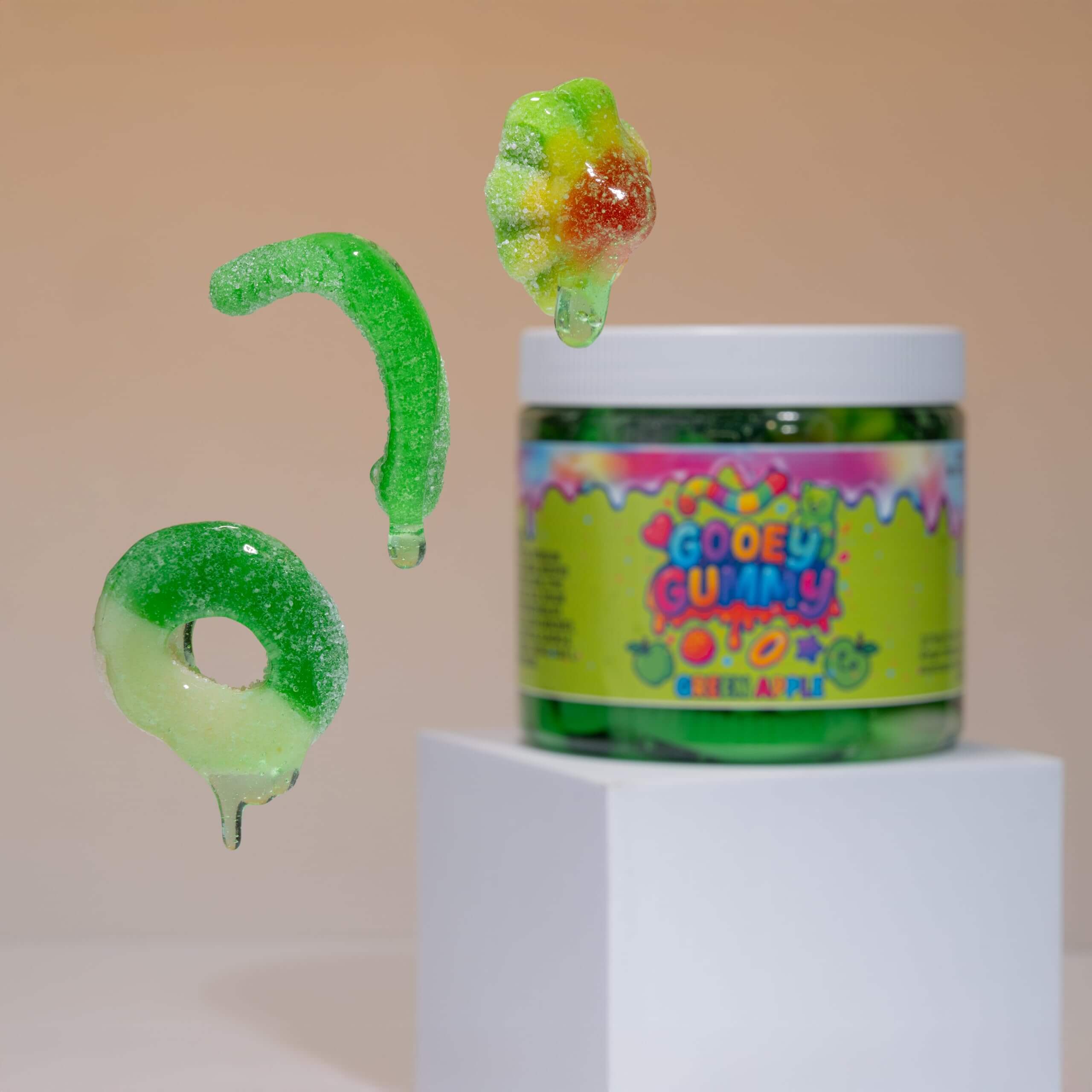 Viral Sour Gooey Gummies in green and cherry flavors flying above a 22 oz jar.