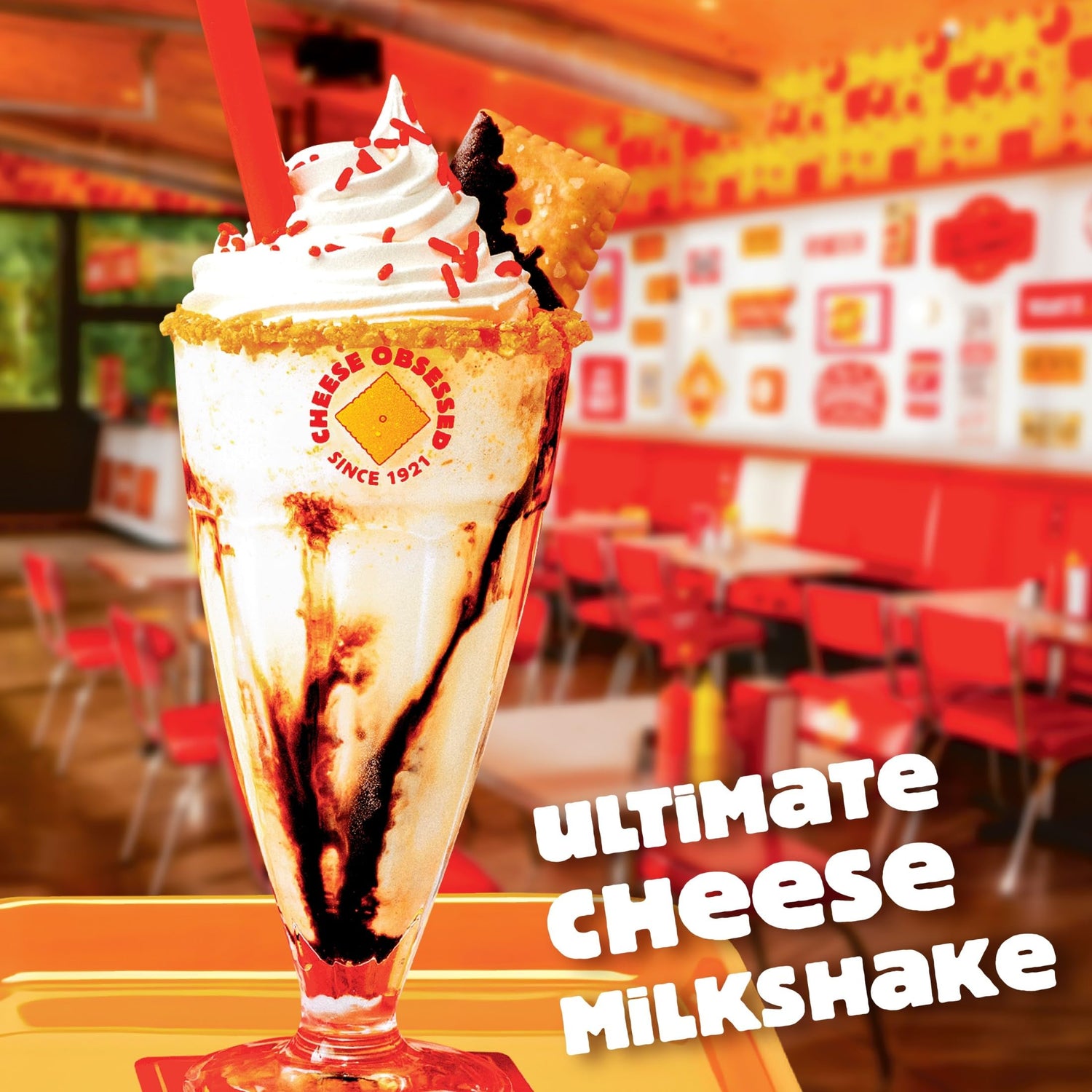 Ultimate Cheese Milkshake topped with whipped cream and a cookie, served in a colorful diner setting. Cheez-It Hot and Spicy Crackers
