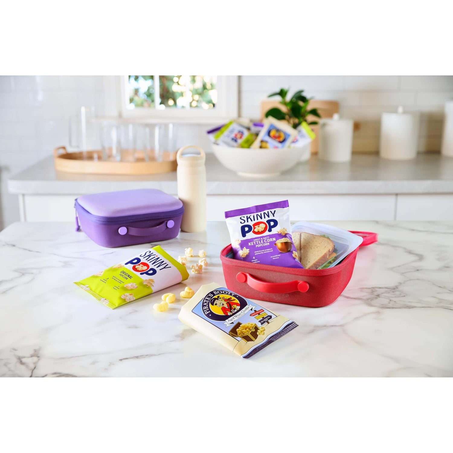 SkinnyPop Family Favorite Variety Pack with snacks in colorful containers on a kitchen counter.