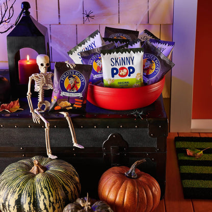 SkinnyPop Family Favorite Variety Pack in a red bowl surrounded by seasonal decorations and snacks.